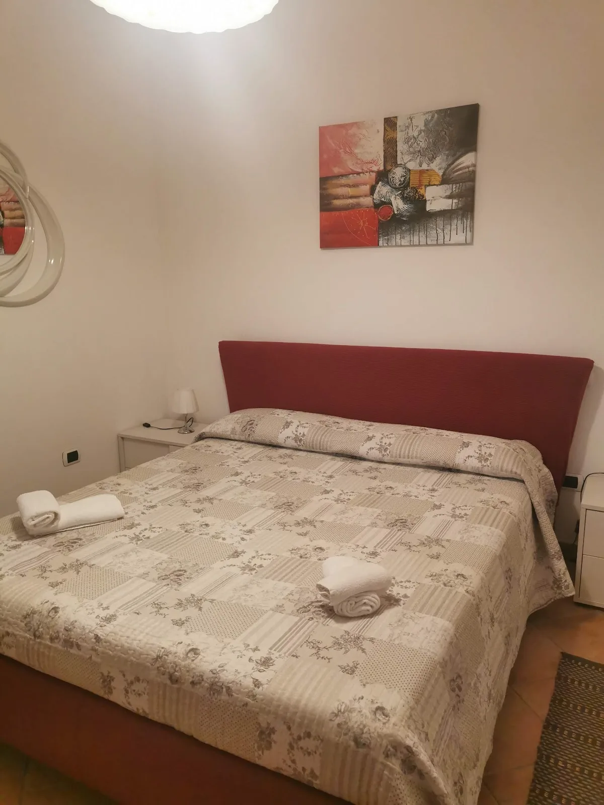 Camera matrimoniale con testiera rossa, letto ampio e biancheria fresca
