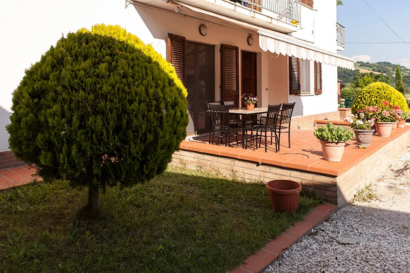La terrazza esterna in cotto con tavolo e sedie, affacciata sul giardino curato del B&B
